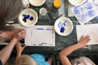 Lapset maalaamassa aikuisen opastuksella