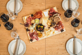 Pöydällä kattaus sekä tapas-lautanen ja viiniä