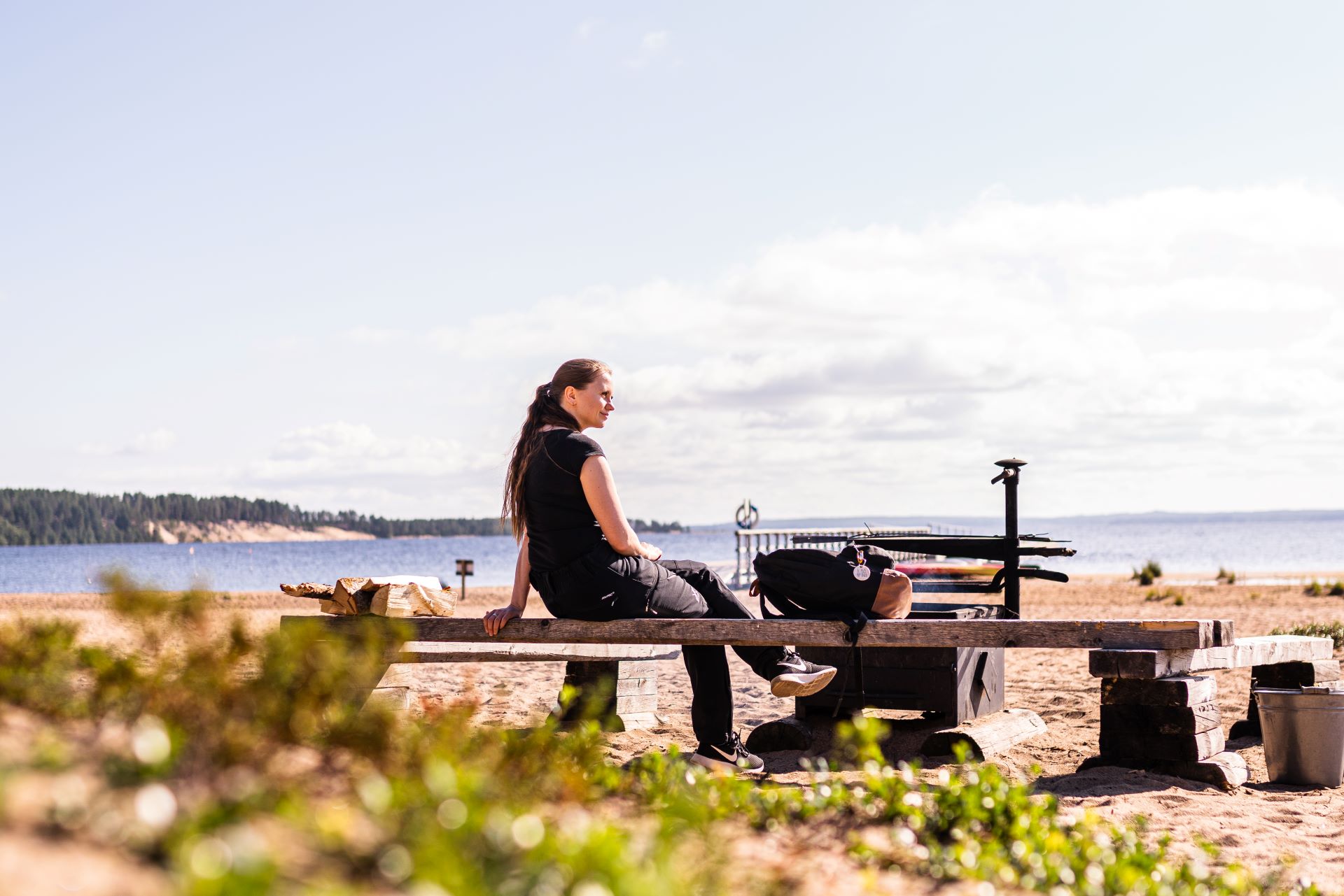 Nainen istuu nuotipaikalla Ärjänsaaren rannalla.